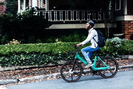 A person riding a bicycle in front of a building  Description automatically generated